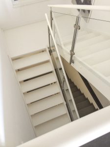 Weiß lackierte Treppe mit Podest und seitlich aufgesetztem Glasgeländer