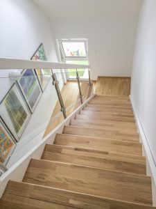 Treppe mit Eichentrittstufen, weiß lackierten Wangen und seitlichem Glasgeländer