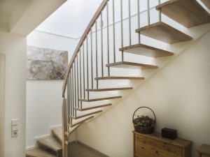 Treppe mit Trittstufen aus Eichenholz, weißer Zahnwange und Edelstahlsprossen
