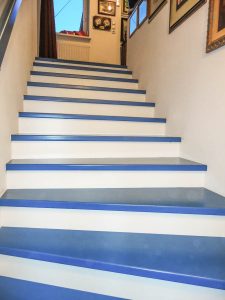 Azurblaue Trittstufen und gleichfarbiger Wandhandlauf, mit weißen Setzstufen