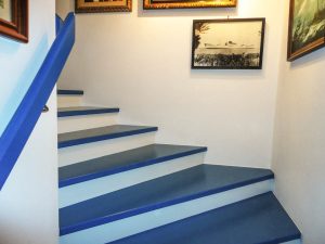 Azurblaue Trittstufen und gleichfarbiger Wandhandlauf, mit weißen Setzstufen