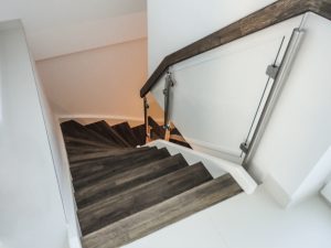 Treppe mit gebeizten Tritt- und Setzstufen, weiß lackierten Wangen und seitlich aufgesetztem Glasgeländer